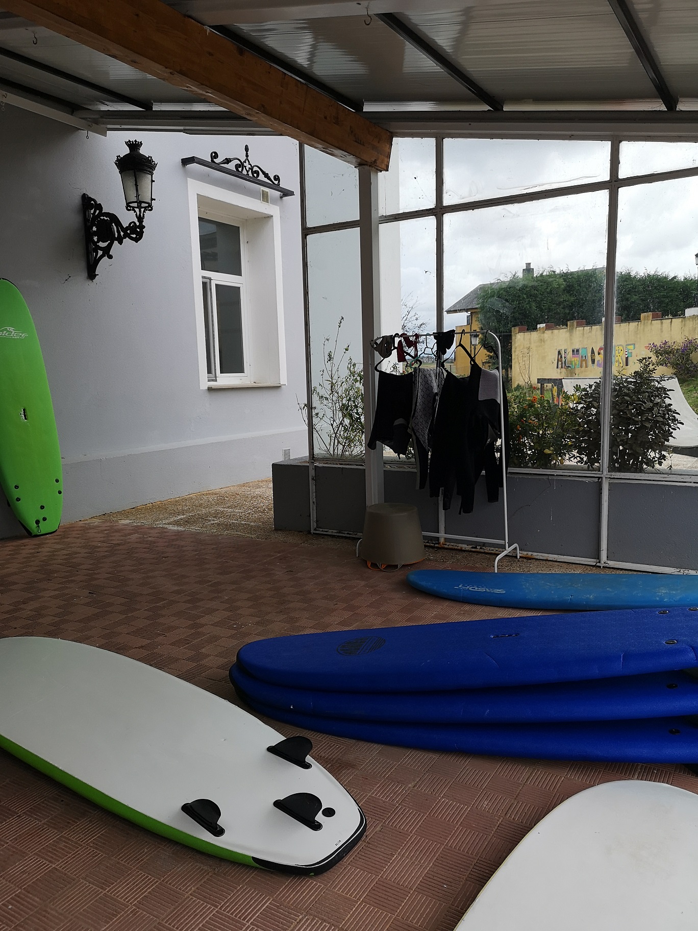 Terraza cubierta de las instalaciones con tablas y ropa para la práctica del surf